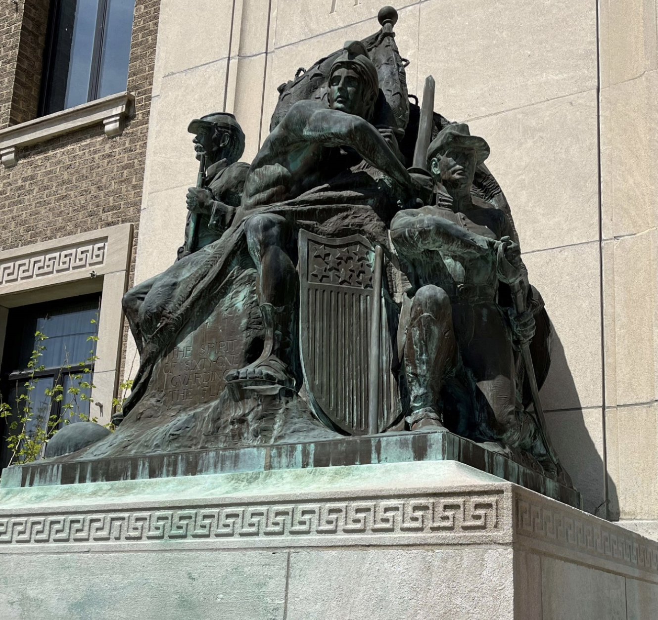 An aged bronze sculpture of soldiers in uniform on the outside of the coliseum